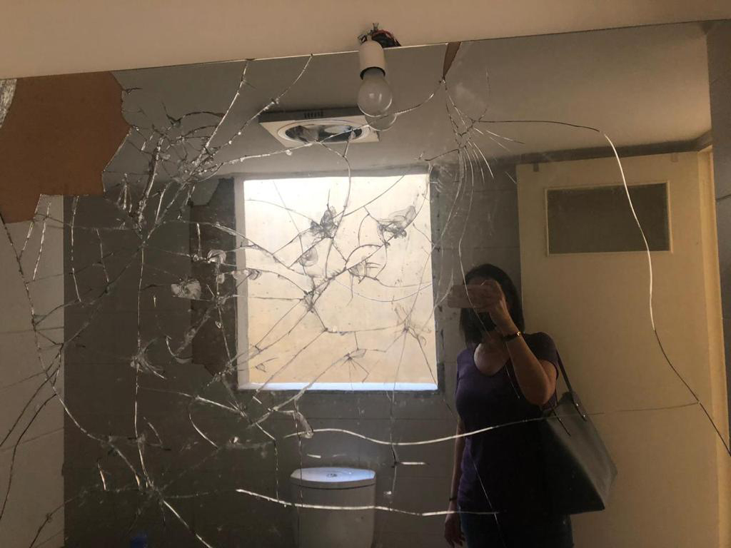 A woman photographs broken glass in a home