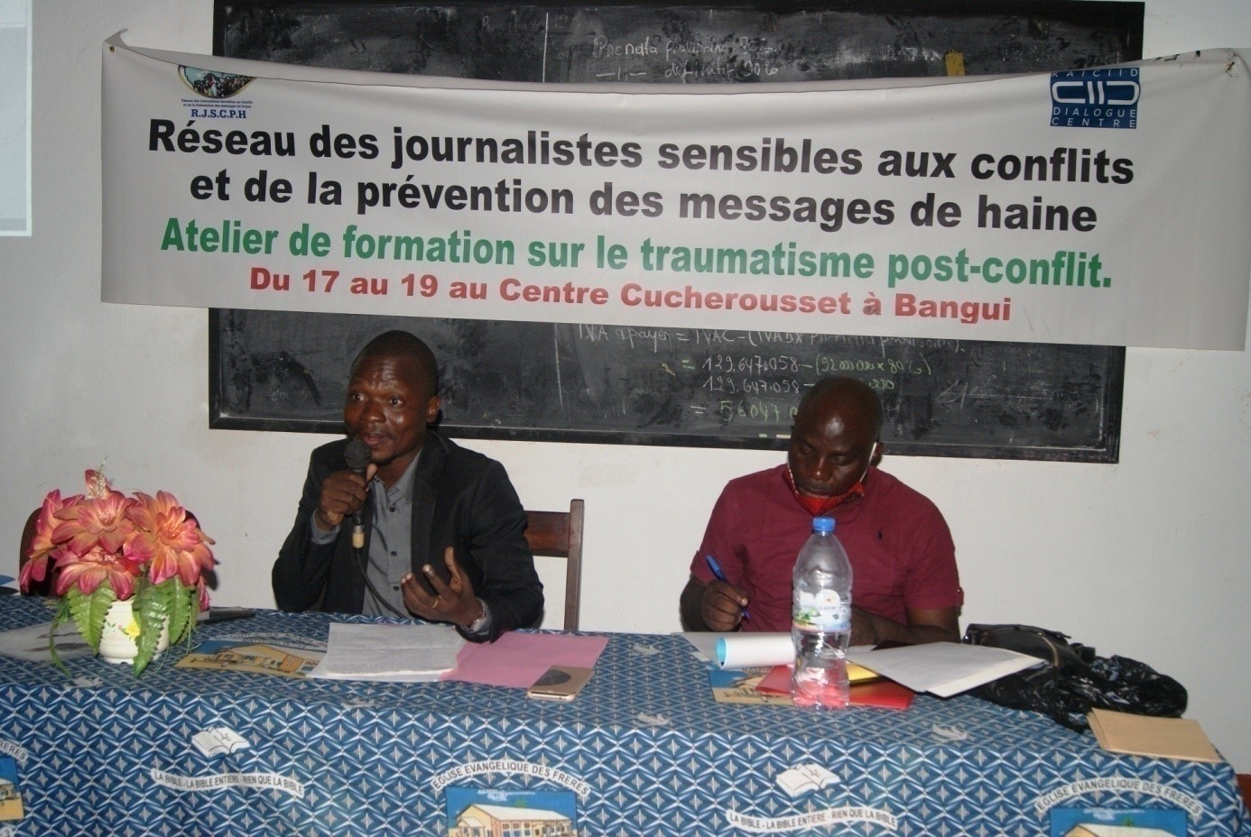A man sitting at a table speaks at a KAICIID training on conflict sensitive journalism
