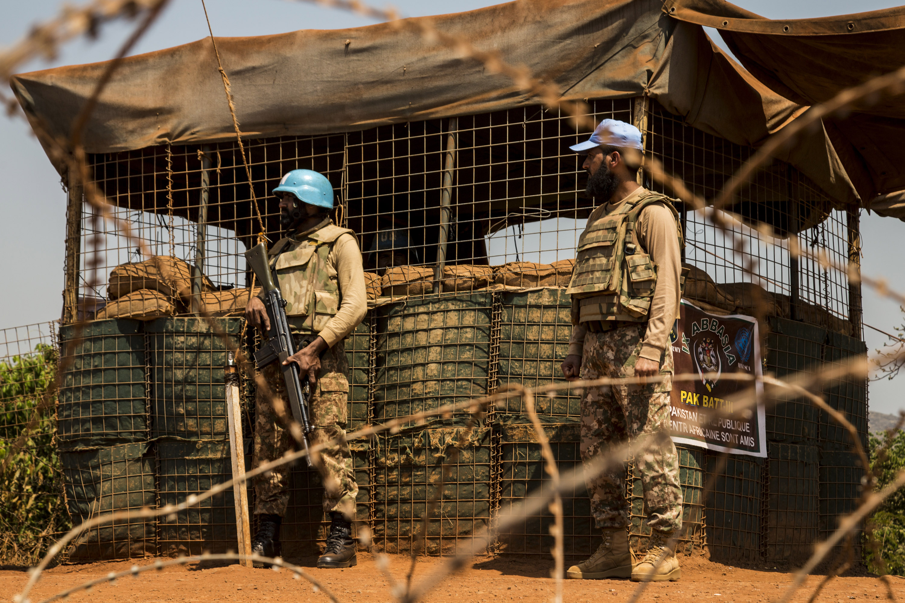 Two UN Peacekeepers stand behind barbed wire 