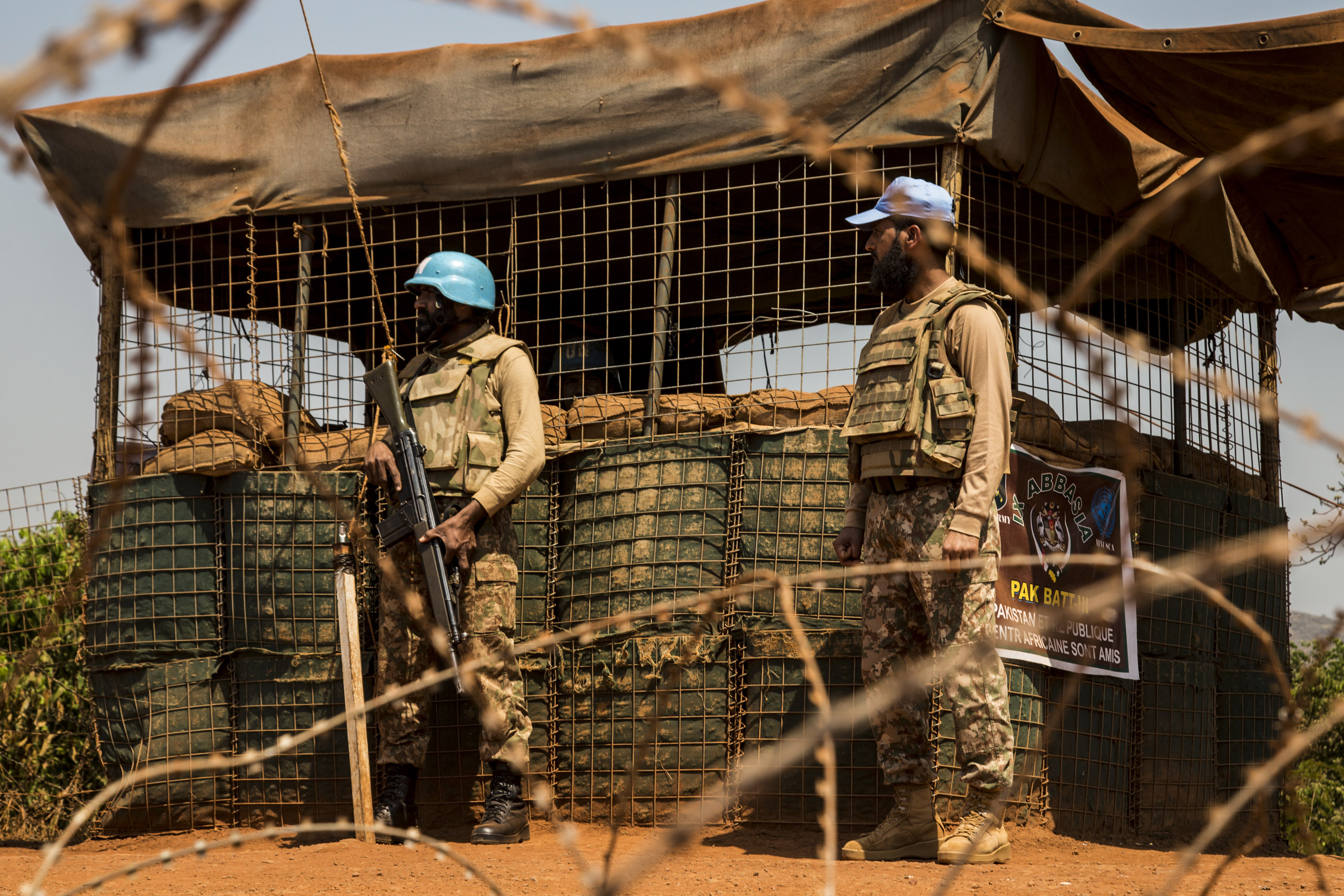 Two UN Peacekeepers stand behind barbed wire