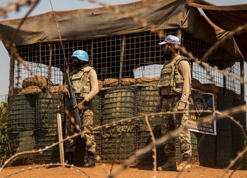 Two UN Peacekeepers stand behind barbed wire 