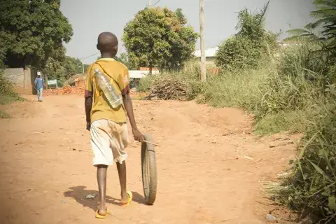 A child rolls a discarded tire in the late morning sun. Photo: Kaleb Warnock/KAICIID