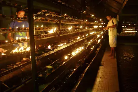 A man lights a candle in prayer. The tour concluded with quiet reflection in the garden of the temple complex under a sapling from the Bodhi tree, the tree under which the Buddha sat when he reached enlightenment. A Man Lights a Candle in the Garden