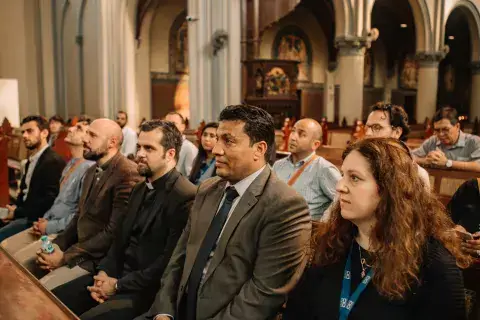 A group of KAICIID Fellows sit together in a cathedral