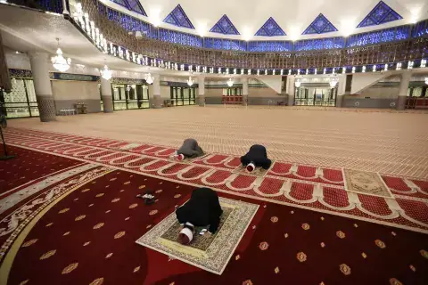 رجال دين مسلمون يمارسون التباعد الجسدي في أثناء أداء صلاتهم