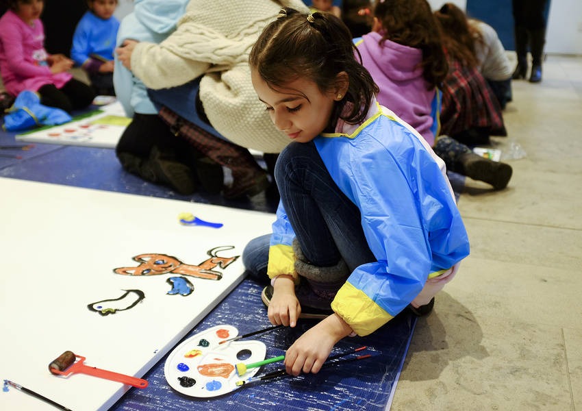 A young asylum seeker chooses among paintbrushes. The children’s work was later exhibited at KAICIID.