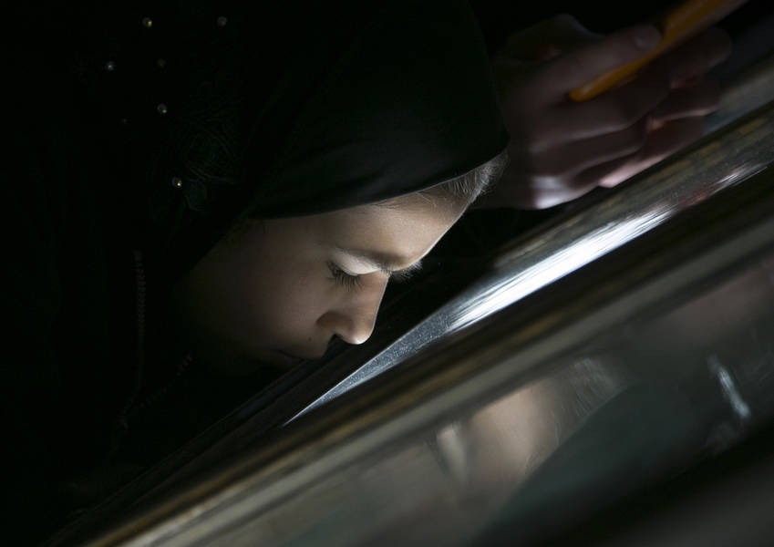 A young asylum seeker peers into a display case in a museum.